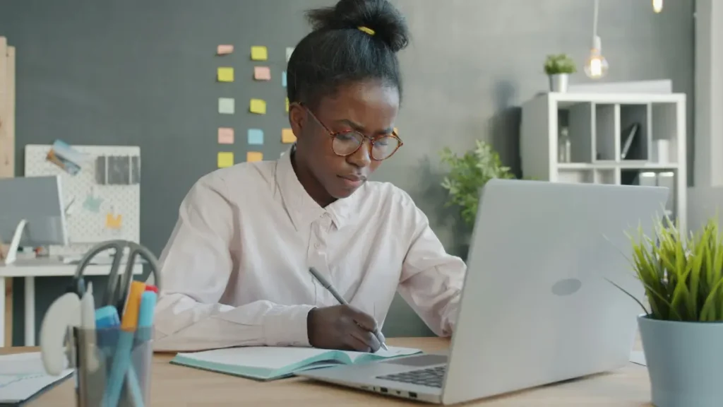Black British woman planning how to pay for flights in installments while researching options on laptop at home office
