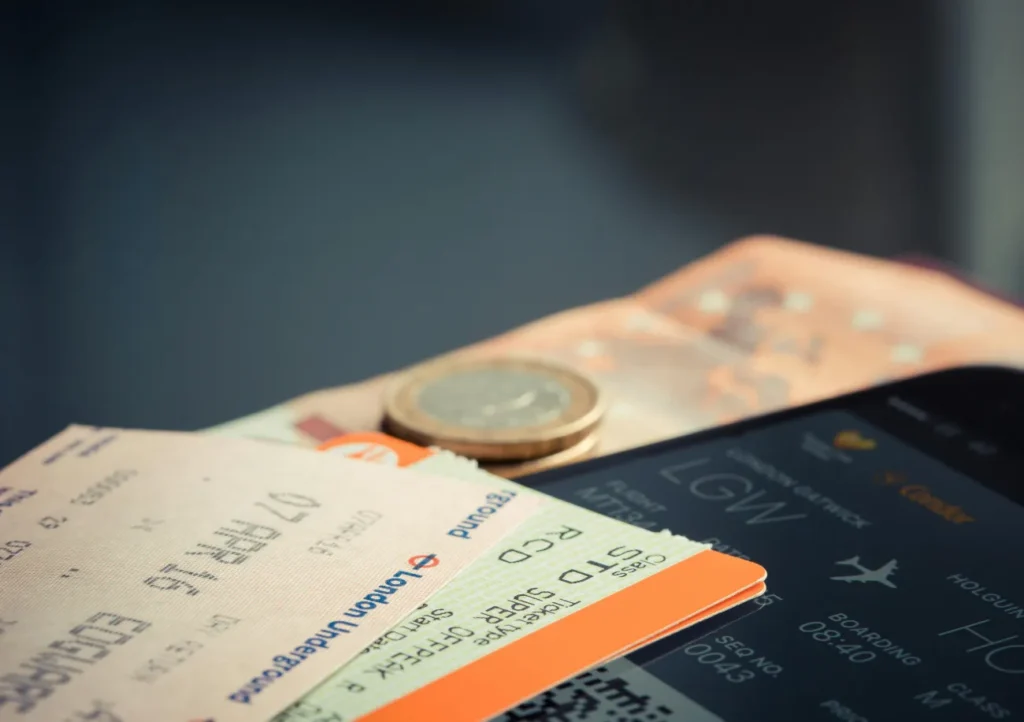 Flight tickets and coin on a table representing pay weekly flight booking in the UK