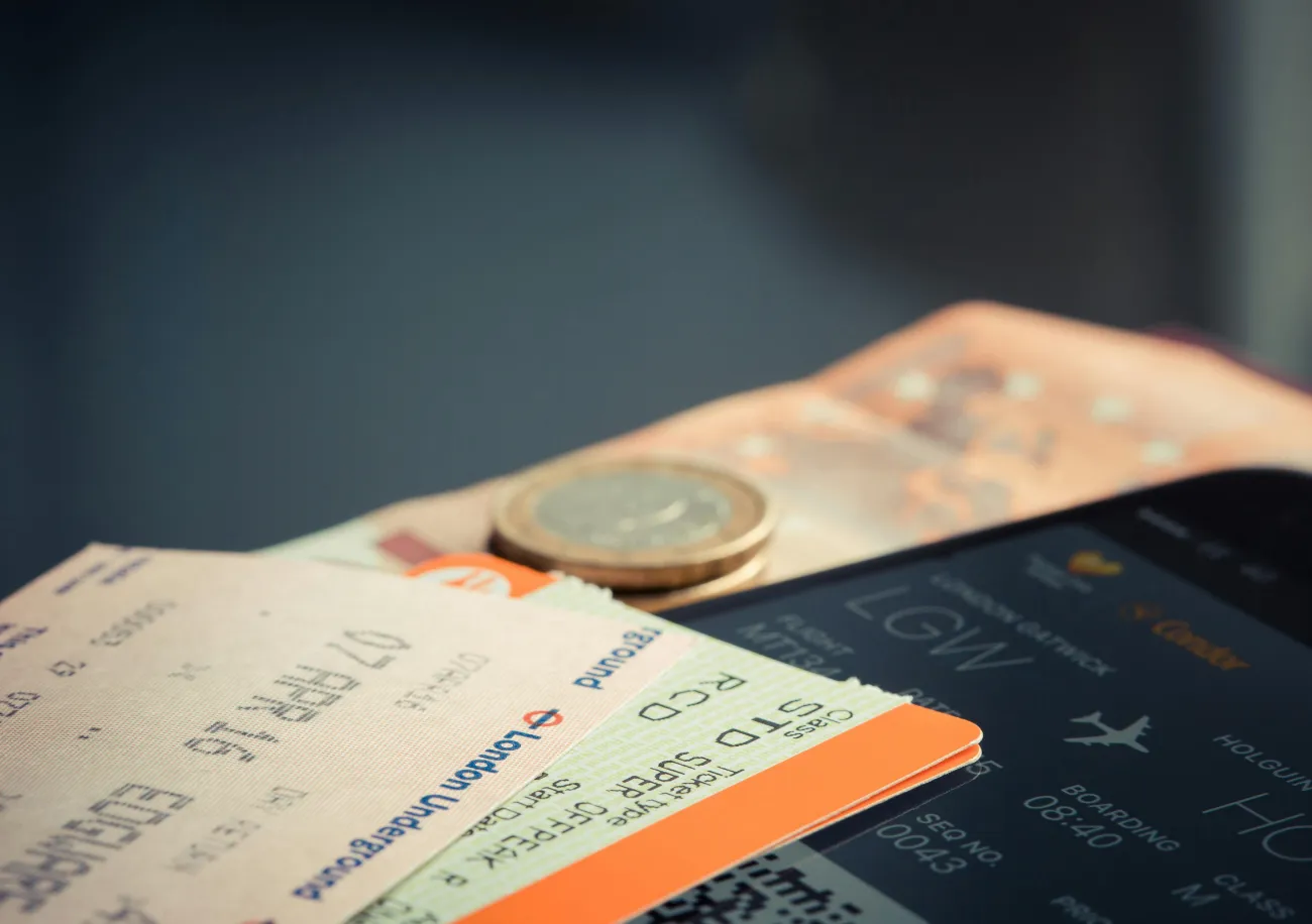 Flight tickets and coin on a table representing pay weekly flight booking in the UK